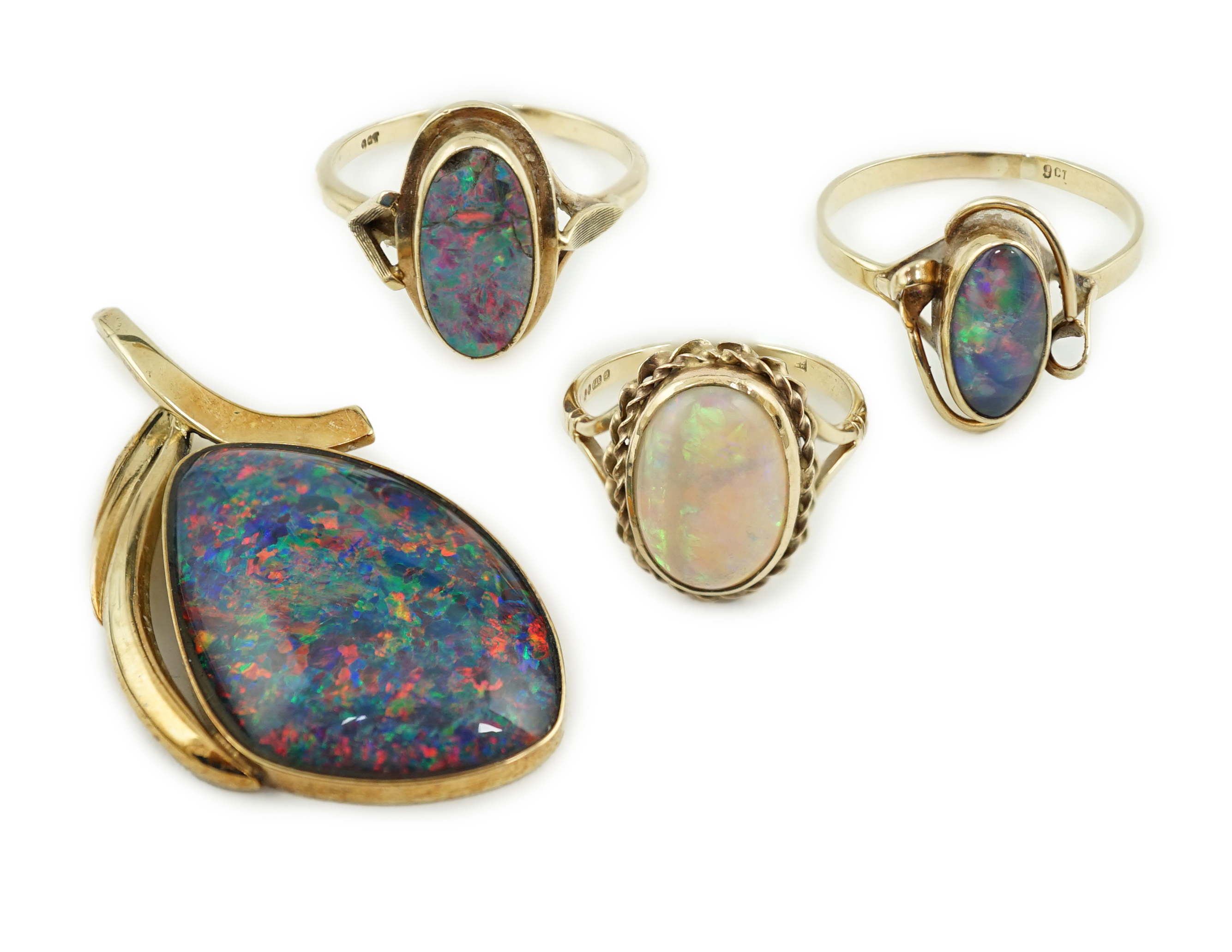 A modern 14k gold and black opal set pendant, 44mm, together with three assorted 9ct gold and single stone cabochon opal set rings